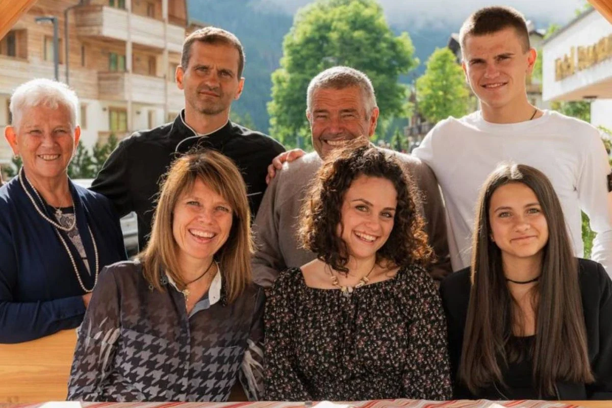 Un gruppo di sette persone sorride all'aperto in una giornata soleggiata.