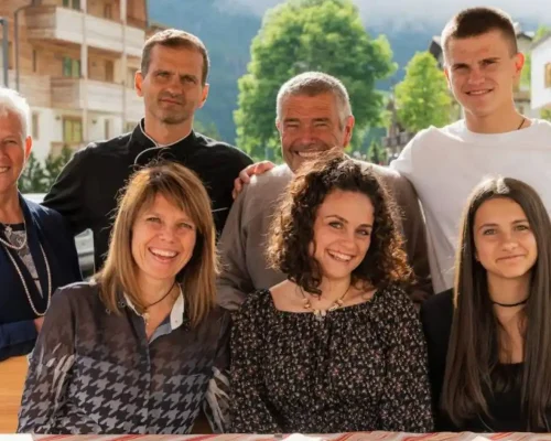 Un gruppo di sette persone sorridenti riunite all'aperto, in un ambiente montano.