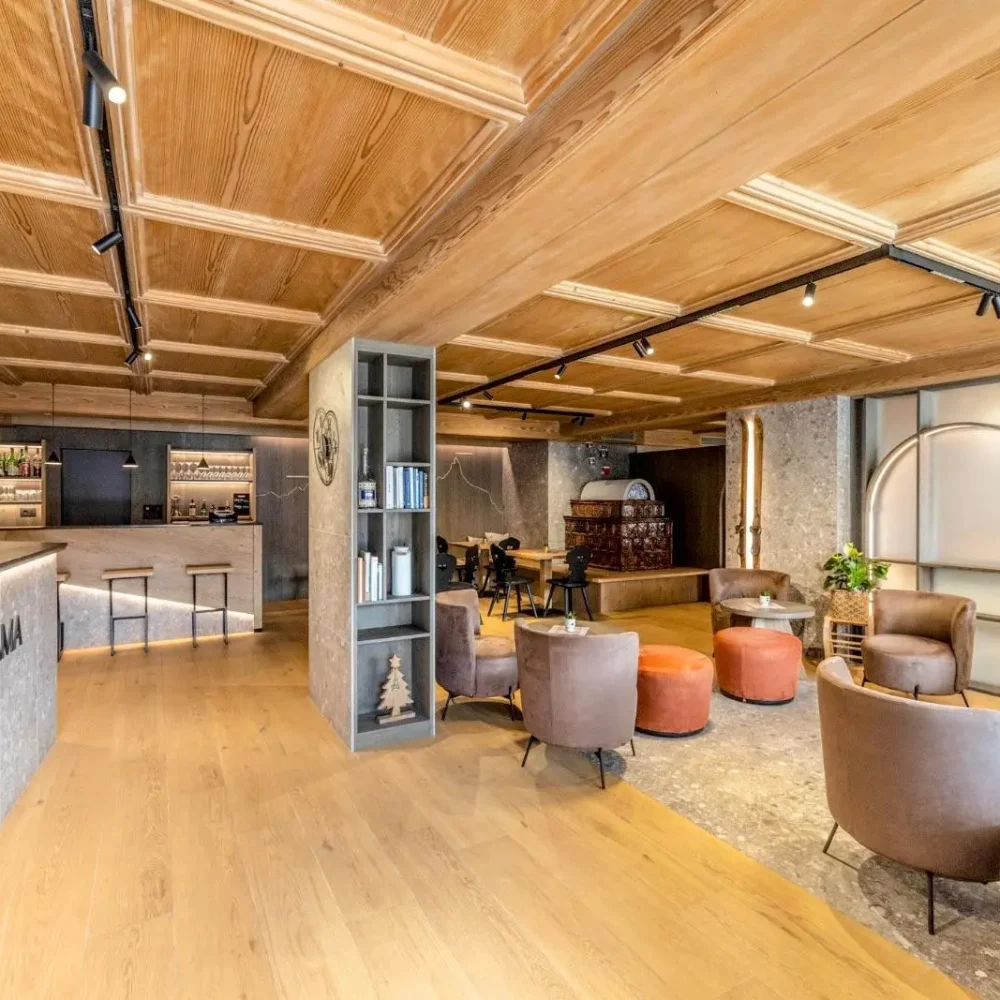 Lobby di un hotel con arredi moderni, pavimento in legno e area bar accogliente.