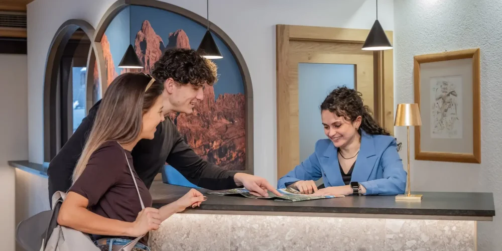 Una coppia riceve informazioni turistiche da una receptionist in un hotel.